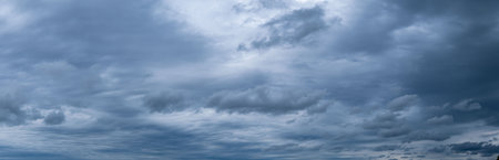 Panorama of cumulus fluffy white and dark gray storm clouds in rainy weather.の写真素材