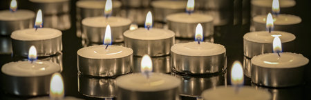 panoramic view of many candles burning in the dark. trembling flames of burning candles on a dark background.の写真素材