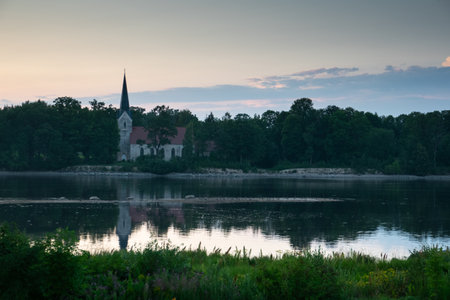 Catholic Church on the bank of the river at sunset. Evening landscape.の写真素材