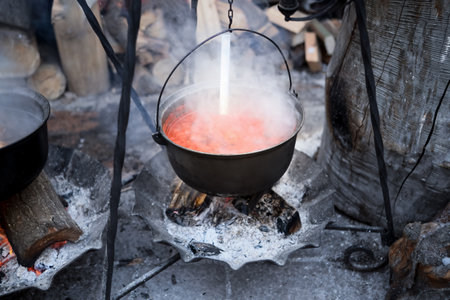 Cooking traditional soups on an open fire in a cauldron on a holiday. Soup with meat and chili.の写真素材