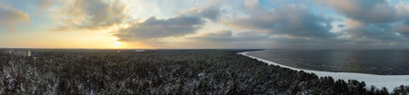 Sunrise over a calm bird's eye view of the sea and forest. Dramatic sunset on the Baltic sea in winter.の写真素材