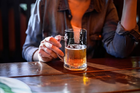 a woman holding a mug of draft lager beer in her hands. rest with drinks, tasting, people and holidays concept.の写真素材
