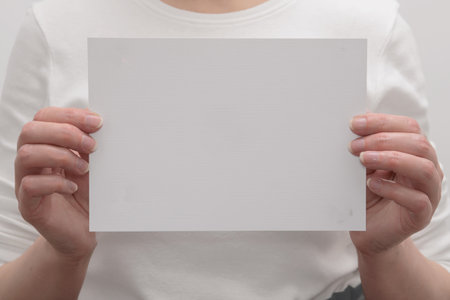 Female hands hold a blank sheet of paper. mockup for agenda or activity information.