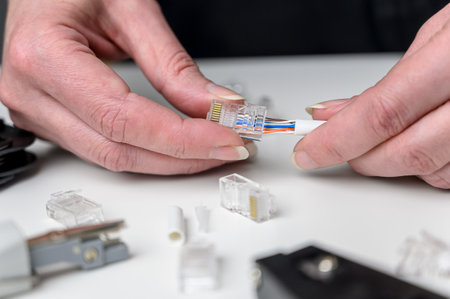 A woman's hand inserts an internet cable into a clamp connector. utp ethernet network cable plug....