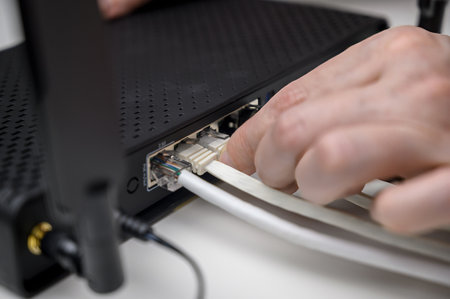 A woman's hand connects an internet cable to a router socket. Fast and wireless internet conceptの写真素材