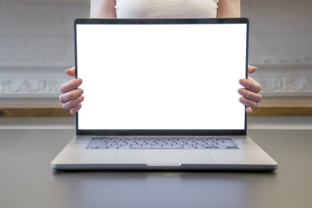 A woman is holding a laptop lid with a blank screen. Laptop on the table.の写真素材