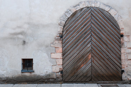 vintage wooden door on the gray wall. a large wooden door on the side of a buildingの写真素材