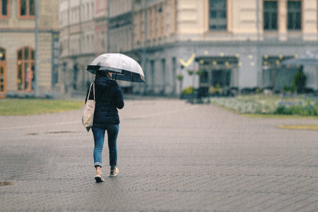 a woman with a transparent umbrella walks through the city on a rainy day.の写真素材