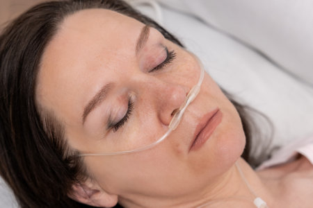 Portrait of a woman in a hospital bed with an oxygen mask. Unhealthy woman suffer from serious viral illness.の写真素材