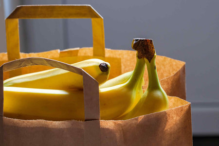 bananas in a paper bag. a bag of groceries in the room on the table.の写真素材