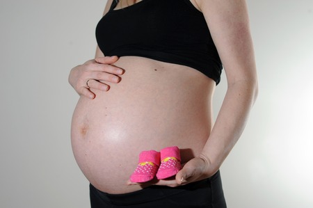 Pregnant woman holding a baby shoes