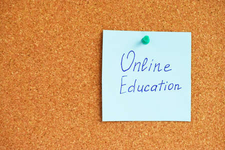 Online Learning written on a piece of paper or note, cork board background.の写真素材