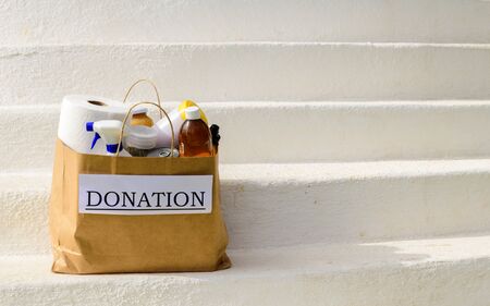 A bag of donations, with food and cleaning supplies waits to be picked up outside on white stepsの写真素材