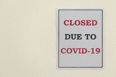 A 'Closed due to Covid-19' sign hangs on a wall during the Coronavirus Pandemicの写真素材