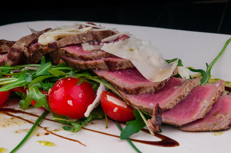 Medium rare steak served on a plate with vegetables and cheeseの写真素材