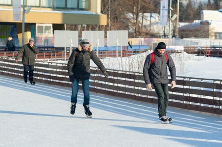 MOSCOW, RUSSIA - JANUARY 22, 2019: Two young guys and senior man skating in VDNKh on winter sunny day. VDNKh is permanent general purpose trade show and amusement park.のeditorial素材