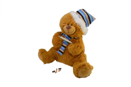 isolate the macro children's toy teddy bear in a scarf with tablets takes temperature a mercury glass thermometerの写真素材