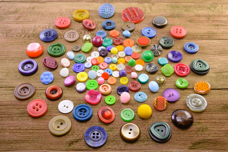 macro handful of multi-colored buttons for clothes on a wooden backgroundの写真素材