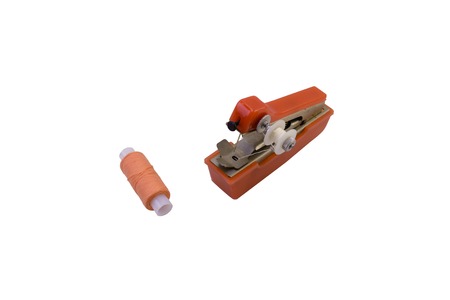 the macro small manual machine for sewing. The small mechanical manual machine for sewing. The sewing machine of coral color and coral threads on the reel on a white background, isolateの写真素材