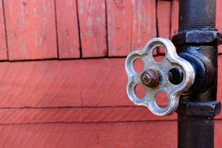 old gate valve on pipe connection black color on a wooden backgroundの写真素材