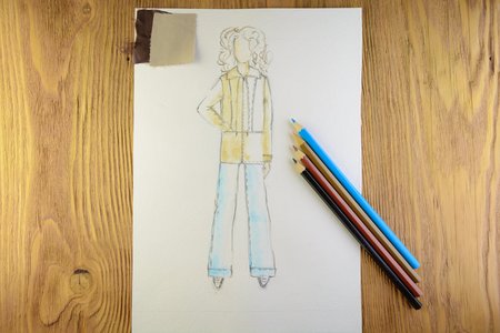 the drawing of designer clothes pencils on paper. background wooden table.