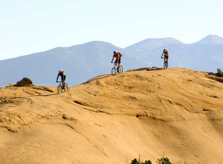 Mountain bikers climb rugged slickrock in Moab, Utahの写真素材