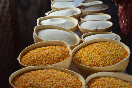 Baskets filled with vibrant yellow corn kernels and finely milled white flour are displayed on a market stall,の写真素材