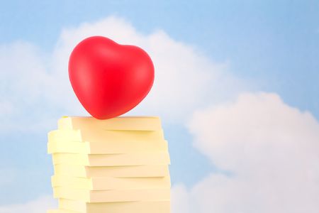 Heart on Stack of Sticky Notes, Representing Office Romance, on Sky Backgroundの写真素材