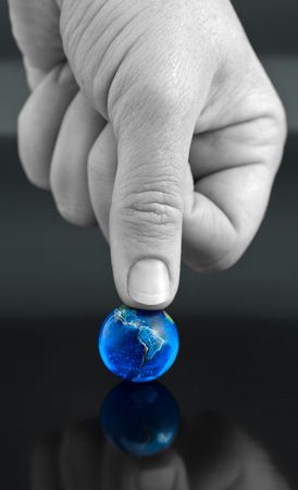 Thumb Pressing Down on Bright Blue Marble Globeの写真素材