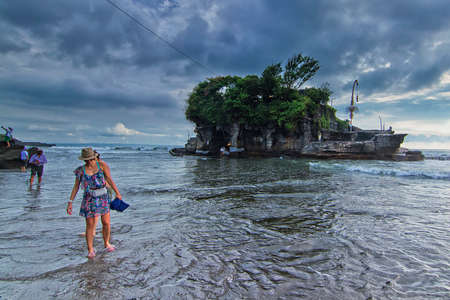 Tanah Lot, Bali - November 25th, 2017: Tourist walking on the beach during low tide in front of the Tanah Lot main temple. Tanah Lot is one of the famous spot in Bali.のeditorial素材