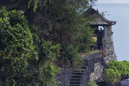 Zoom shot of a temple on top of a cliff with a staircase towards it in Tanah Lot, Baliの写真素材