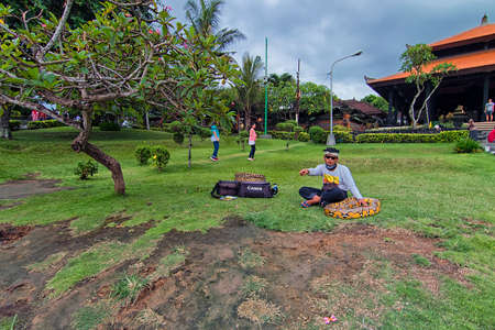 Tanah Lot, Bali - November 25th, 2017: A local entertainer petting his snake as he is getting ready to entertain the tourist with the snake in Tanah Lot, Bali. Tanah Lot is one of the famous tourism spot in Bali.のeditorial素材