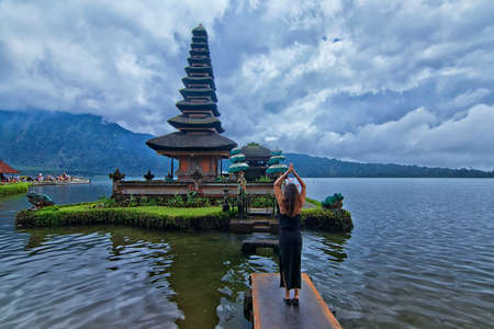 Human interest shot of a tourist giving a spiritual pose in front of Bratan Lake Templeのeditorial素材