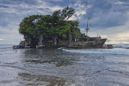 Nature view of the main temple of Tanah Lot in Bali. Observed that the tourist was trying to cross the sea to reach the templeの写真素材
