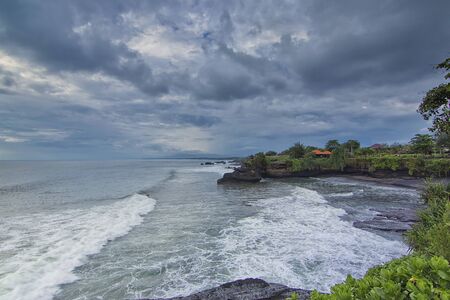 Great landscape view of a wave hitting the beach with a surfer surfing through it. Motion blur effect due to long exposure techniqueの写真素材