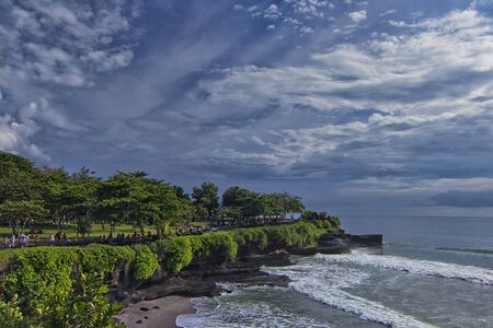 Great landscape view of cliff in Tanah Lot with heavy wave hitting the beachの写真素材