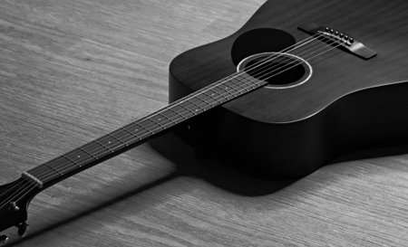 Acoustic guitar on a wooden background. Black and white photo.