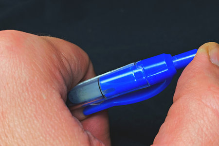 Close-up of a man's hand holding a blue marker.