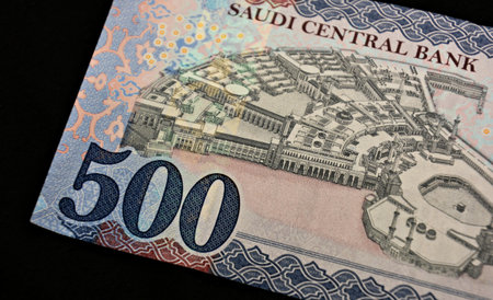 Close-up of a Man's Hand Holding Several Crisp 500 Saudi Riyal Banknotes, Isolated on a White...