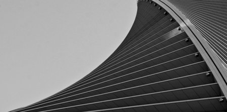 Modern building with curved glass facade reflecting sky. Contemporary architectural design against a...