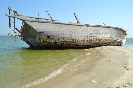 Ruined wreck of a fishing boat stranded on a sandy beach.