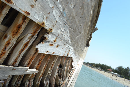 Ruined wreck of a fishing boat stranded on a sandy beach.