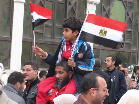 Alexandria, Egypt - February 04, 2011 - Boy carrying flags among demonstrators calling for the resignation of President Mubarak のeditorial素材