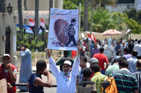 Alexandria, Egypt - July 15, 2011 -Egyptian senior citizen calling for the trial of Mubarak and his regime. Translation of sign text: "The will of the people - The people want to prosecute Mubarak"のeditorial素材