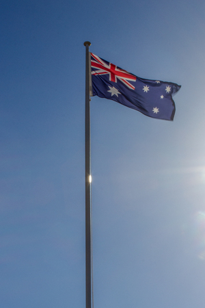 Australian flag slowly waving on the beautiful blue sky in Australiaの写真素材