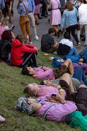 Munich, Germany, 2019 September 19: 4 mans sleeping in a row on the lawn at the Bavarian Oktoberfest in Munichのeditorial素材