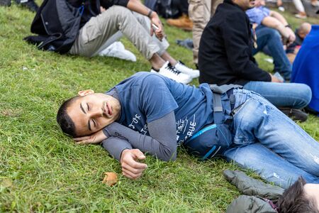 Munich, Germany, 2019 September 19: 4 mans sleeping in a row on the lawn at the Bavarian Oktoberfest in Munichのeditorial素材