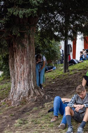 Munich, Germany, 2019 September 19: one jung women with a finger in her moth try to throw up because of to much alcohol behind a tree at the Bavarian Oktoberfest in Munich.のeditorial素材