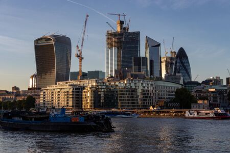 The bold and imposing City of London skyscrapers reflect a golden colour at sunset with a clear sky...