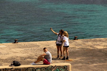 Beautiful consumer tourist couple smiling on city break holiday sightseeing with heads together, using technology smartphone taking selfies outdoors. Fun travel vacation, leisure recreation lifestyle.のeditorial素材